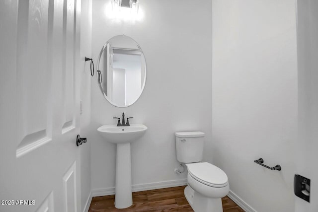 bathroom with a sink, toilet, baseboards, and wood finished floors