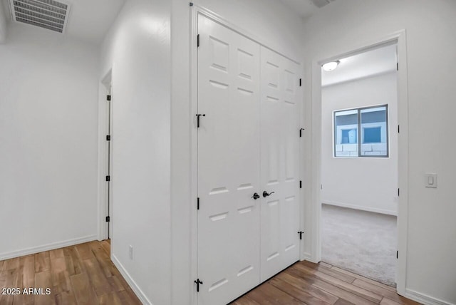 hallway with visible vents, baseboards, and wood finished floors