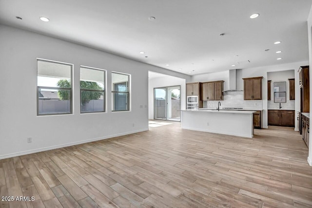 unfurnished living room with recessed lighting, baseboards, light wood-style floors, and a sink