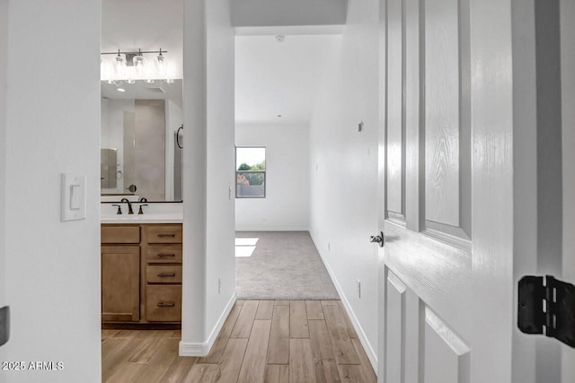 interior space with baseboards, light wood-type flooring, and a sink