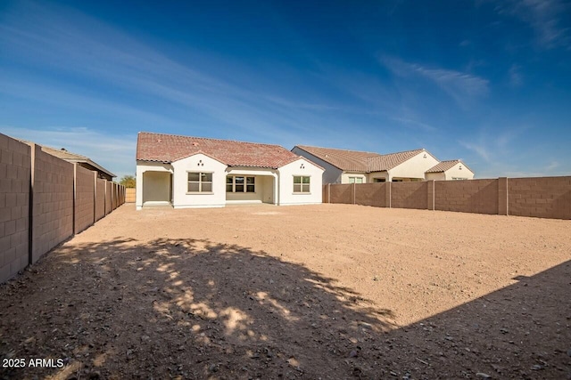 rear view of house with a tile roof and a fenced backyard