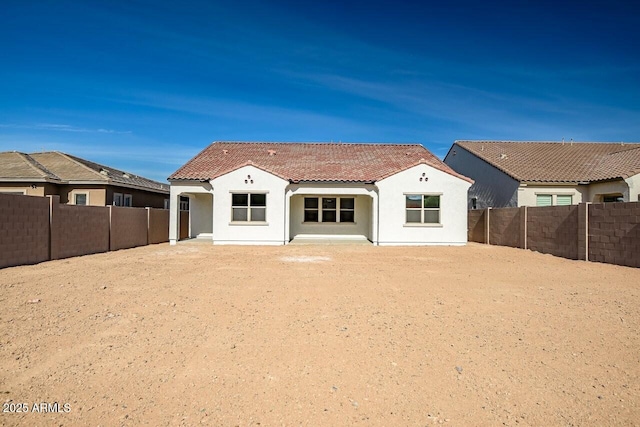 rear view of house featuring stucco siding, a tile roof, and a fenced backyard