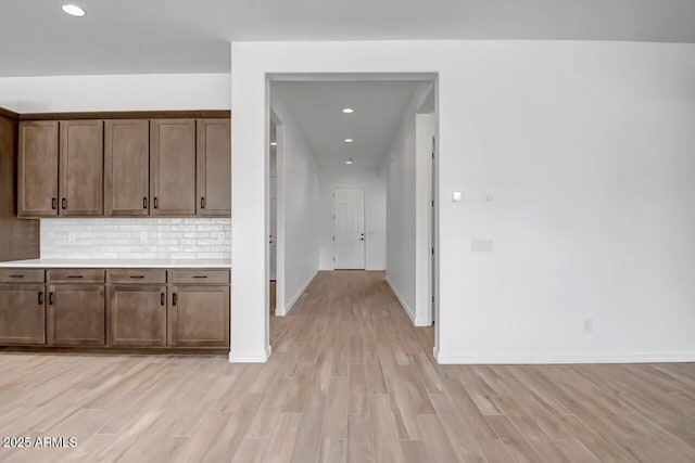 kitchen with light wood-style flooring, recessed lighting, light countertops, decorative backsplash, and baseboards