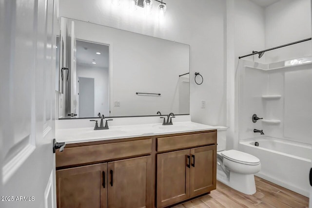 bathroom with a sink, toilet, wood finished floors, and double vanity