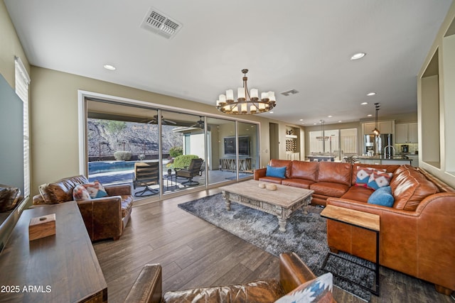 living room featuring dark hardwood / wood-style flooring and ceiling fan with notable chandelier