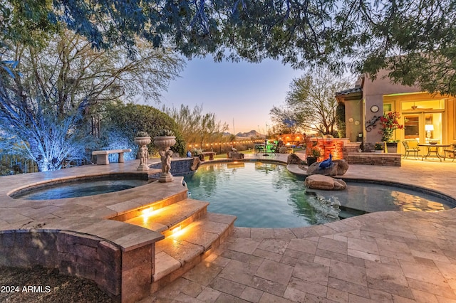 pool at dusk with a patio and an in ground hot tub