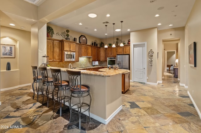 kitchen featuring stainless steel appliances, decorative backsplash, kitchen peninsula, a kitchen breakfast bar, and decorative light fixtures