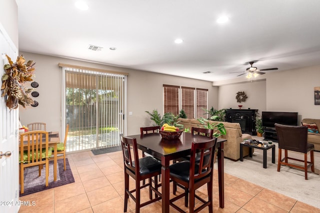 dining area featuring light tile patterned floors, a wood stove, and ceiling fan