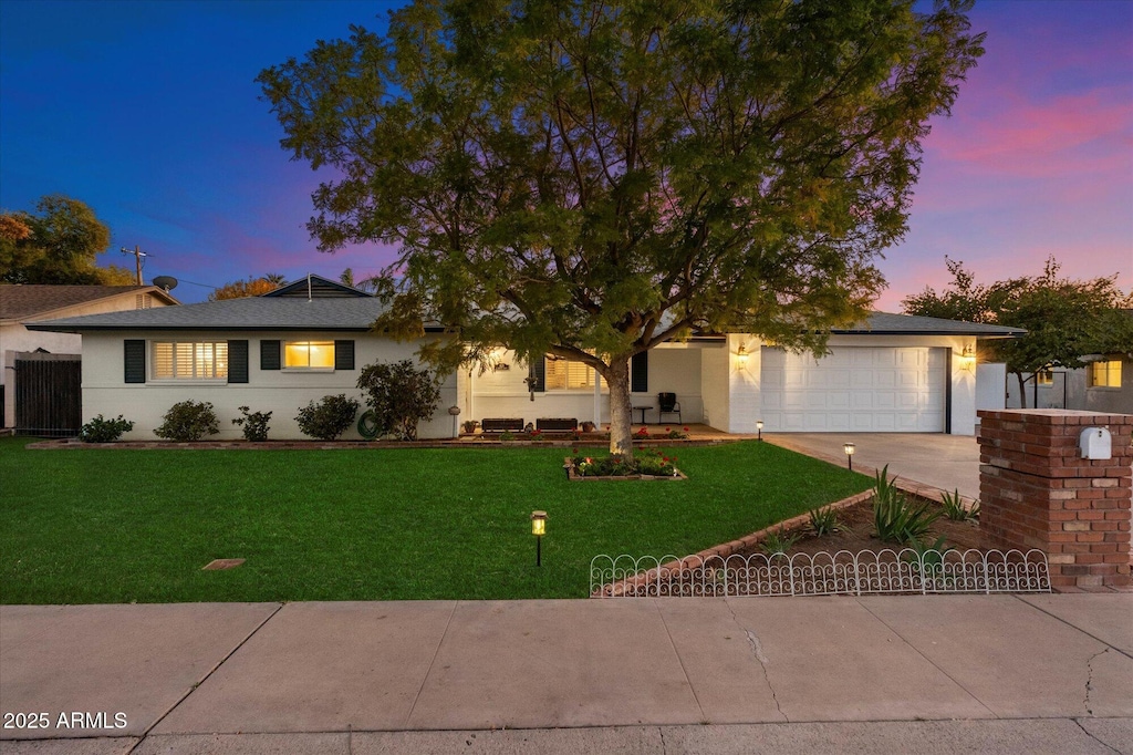 single story home featuring driveway, a garage, and a yard