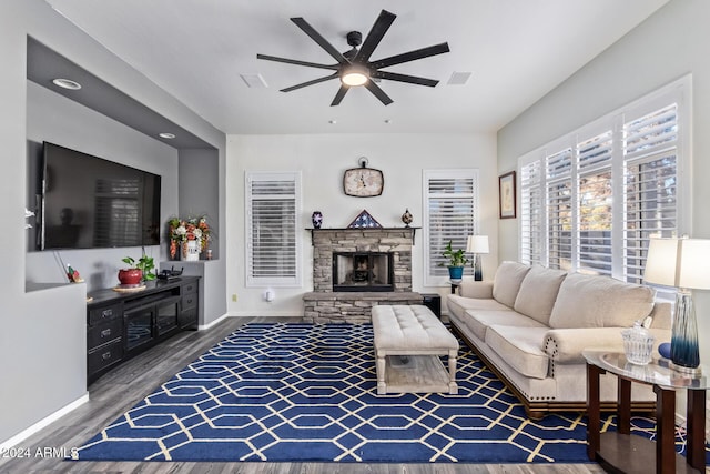 living room with hardwood / wood-style floors, ceiling fan, and a stone fireplace