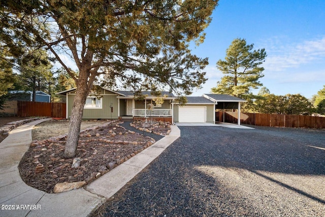 single story home with covered porch, gravel driveway, fence, and an attached garage