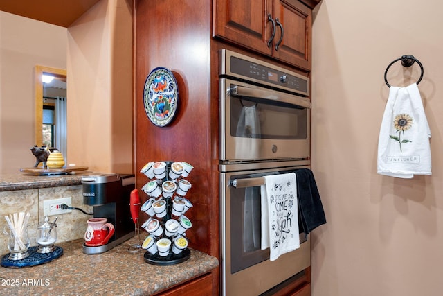 kitchen featuring tasteful backsplash, dark stone countertops, and stainless steel double oven