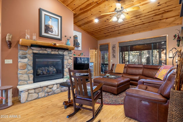 living room with wood ceiling, wood-type flooring, a stone fireplace, and vaulted ceiling