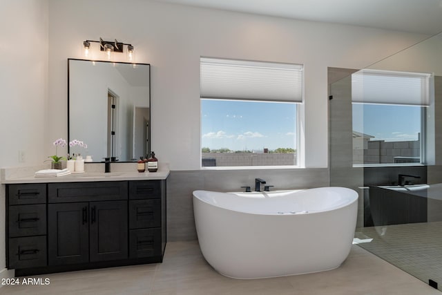 bathroom featuring a tub to relax in, tile patterned flooring, vanity, and tile walls