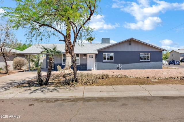 ranch-style house featuring a carport, a chimney, and driveway