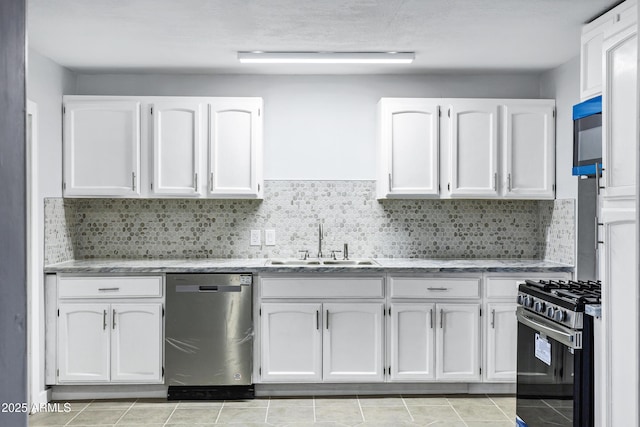kitchen with white cabinets, light stone countertops, appliances with stainless steel finishes, a sink, and backsplash