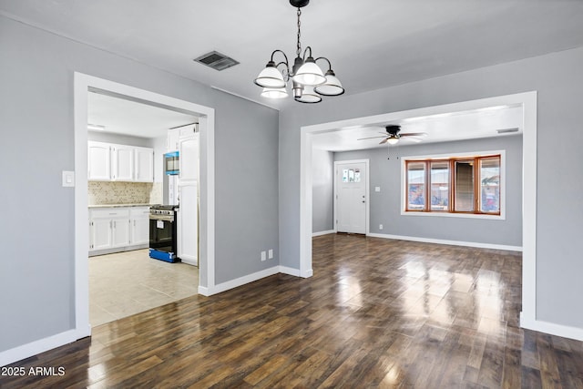 unfurnished dining area featuring visible vents, baseboards, ceiling fan with notable chandelier, and wood finished floors