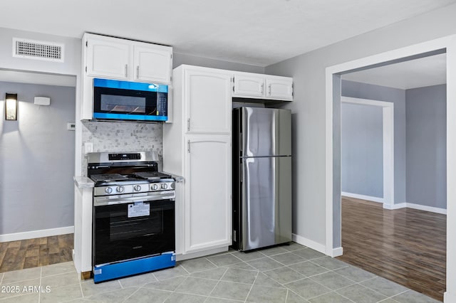 kitchen with stainless steel appliances, baseboards, white cabinetry, backsplash, and visible vents