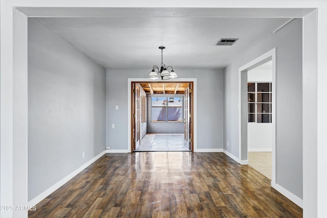 unfurnished dining area with visible vents, dark wood finished floors, baseboards, and an inviting chandelier