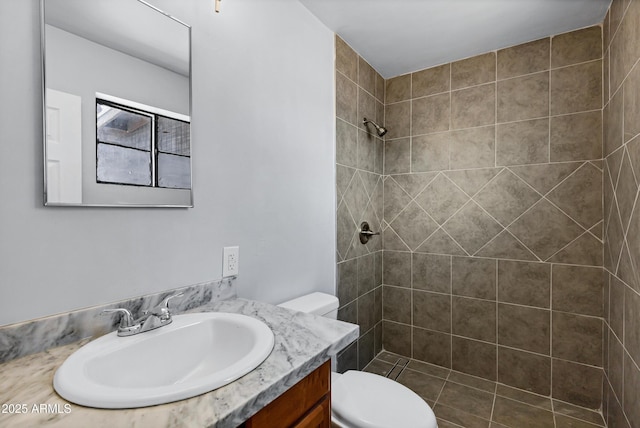 bathroom with vanity, toilet, and tiled shower