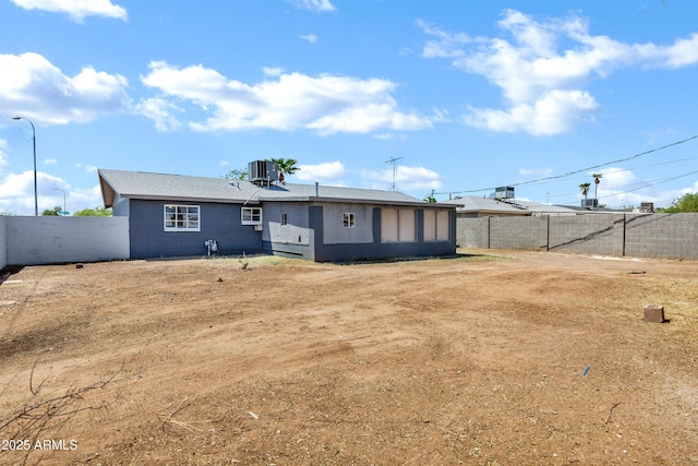 rear view of property with a fenced backyard and central AC