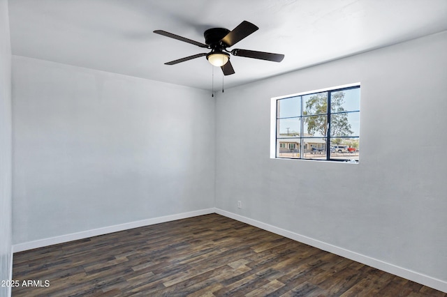 empty room with baseboards, ceiling fan, and dark wood finished floors