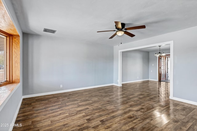 spare room with baseboards, visible vents, ceiling fan with notable chandelier, and dark wood-type flooring