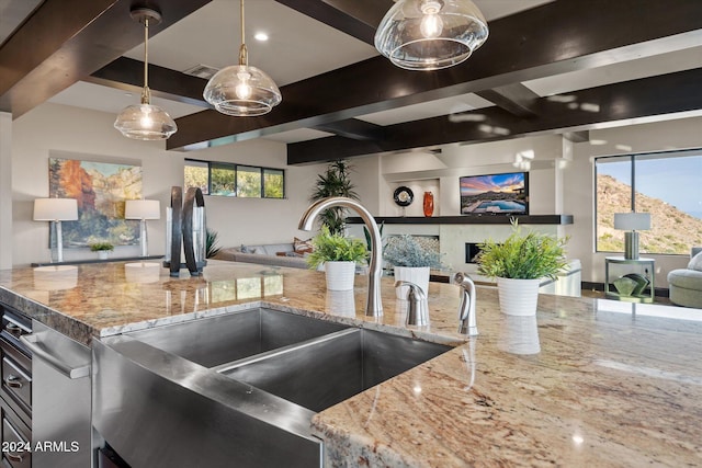 kitchen featuring light stone countertops, hanging light fixtures, and sink