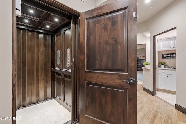 interior details with elevator, beamed ceiling, coffered ceiling, and hardwood / wood-style flooring