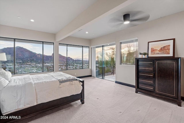 bedroom featuring a mountain view, light carpet, ceiling fan, access to exterior, and beamed ceiling