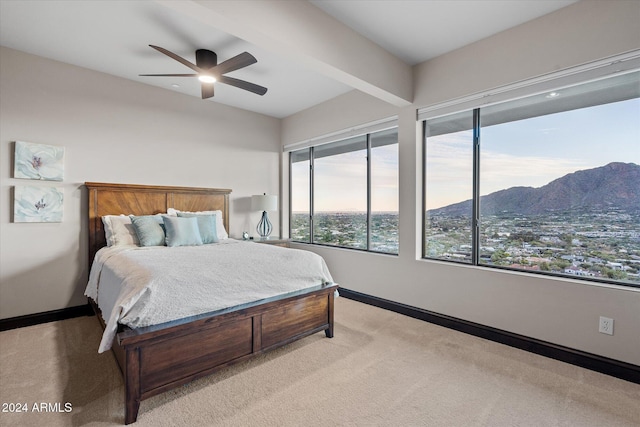 carpeted bedroom featuring a mountain view, beam ceiling, and ceiling fan