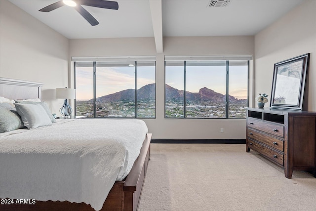 carpeted bedroom featuring a mountain view, ceiling fan, and beamed ceiling