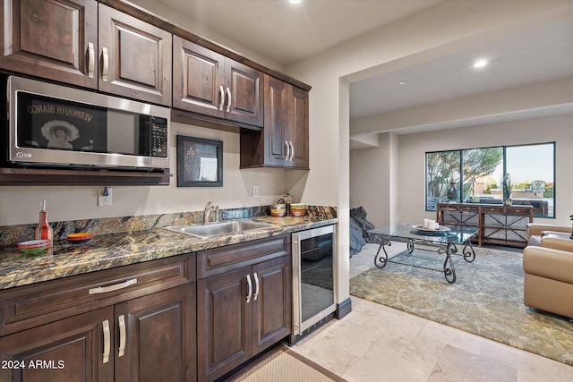 kitchen featuring dark brown cabinetry, sink, wine cooler, and dark stone counters