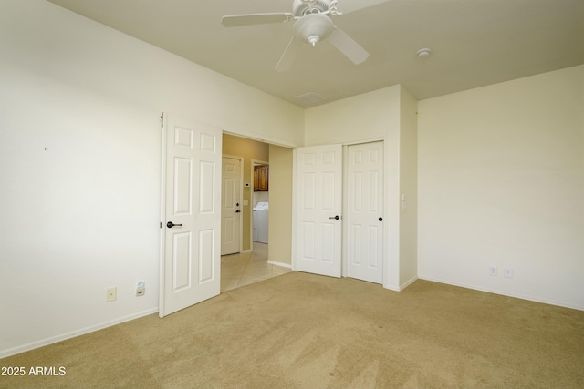 unfurnished bedroom with baseboards, light colored carpet, washer / dryer, a closet, and a ceiling fan