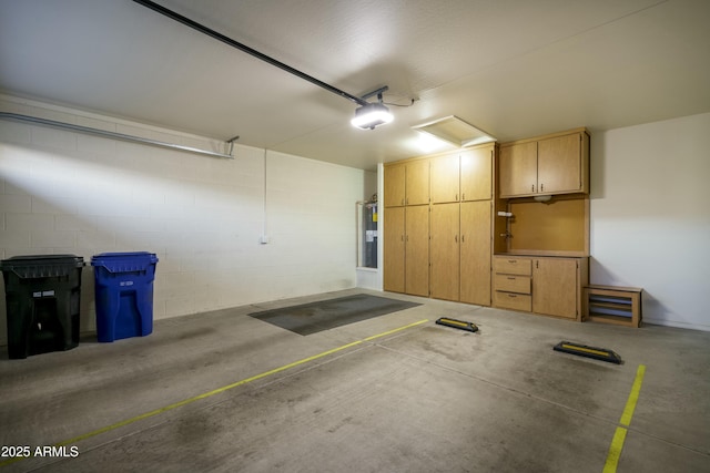 parking garage featuring concrete block wall, a garage door opener, and water heater