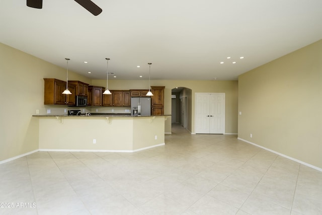 kitchen featuring a kitchen breakfast bar, stainless steel appliances, arched walkways, a peninsula, and baseboards