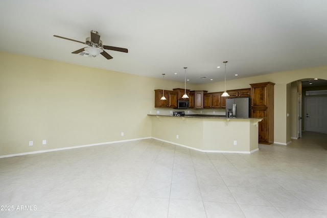 kitchen featuring a kitchen breakfast bar, stainless steel appliances, arched walkways, a peninsula, and baseboards