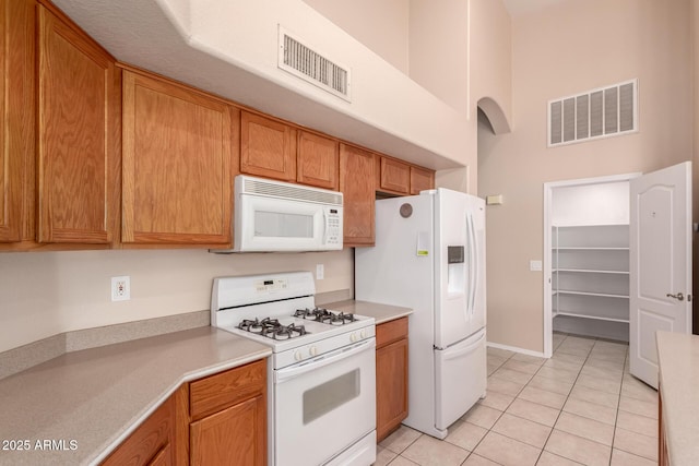 2230 E Whitten St, Chandler, AZ 85225 - kitchen with white appliances, light tile patterned flooring, light countertops, a towering ceiling, and brown cabinetry