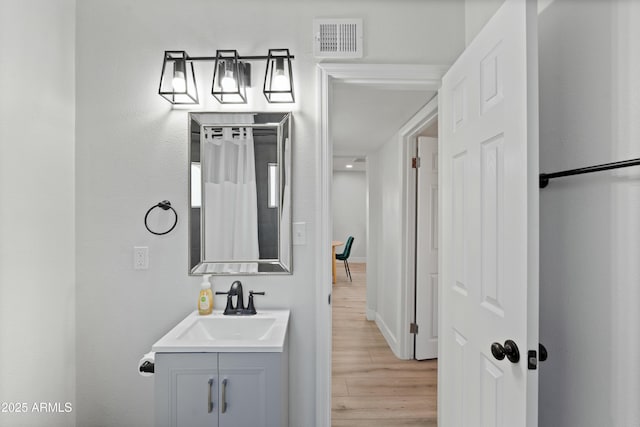 bathroom with vanity, wood finished floors, visible vents, and baseboards