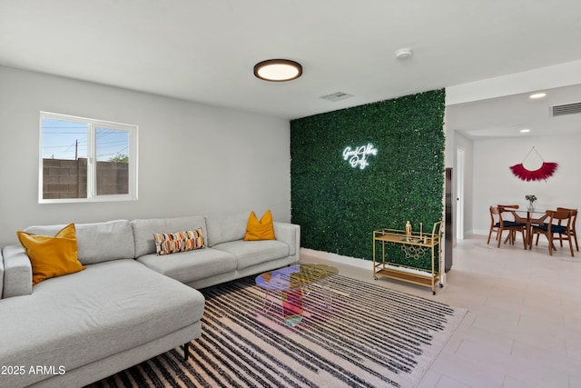 living room with an accent wall, recessed lighting, visible vents, and baseboards