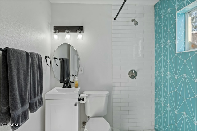 bathroom with a tile shower, vanity, and toilet