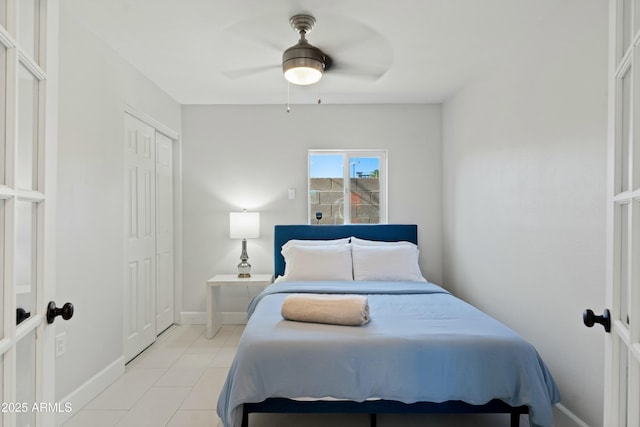 bedroom with a ceiling fan, a closet, light tile patterned flooring, and baseboards