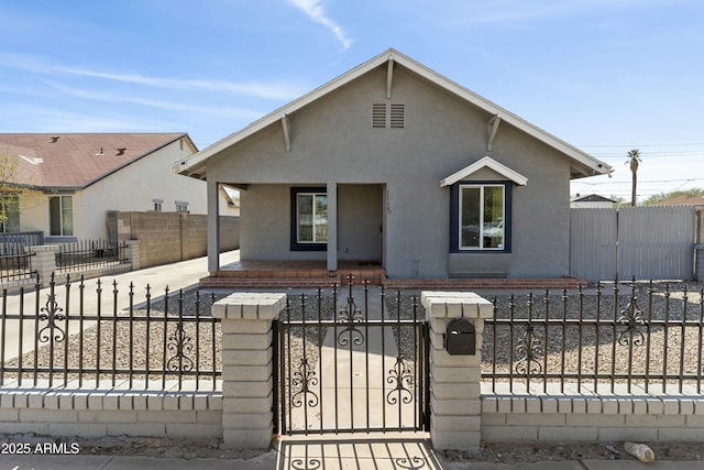 bungalow with a fenced front yard, a gate, a porch, and stucco siding