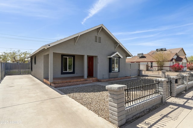 bungalow featuring a gate, fence, and stucco siding