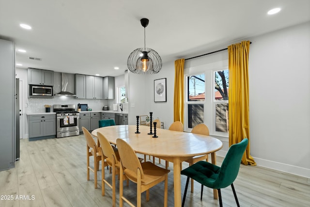 dining space featuring light wood-style floors, a wealth of natural light, and visible vents