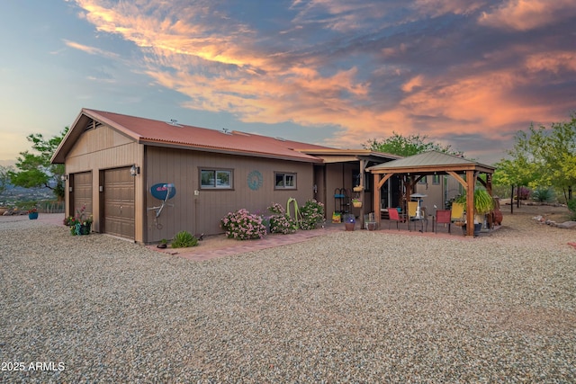 1185 S Camino Cobre Dr, Wickenburg, AZ 85390 - back of property at dusk with a gazebo, metal roof, and a detached garage