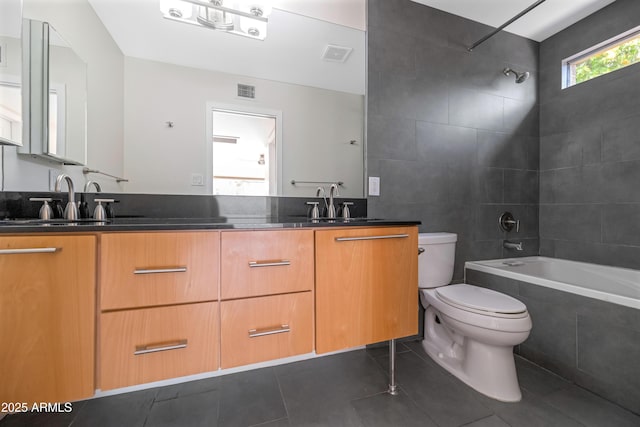 full bathroom with tile patterned flooring, toilet, tile walls, tiled shower / bath, and vanity