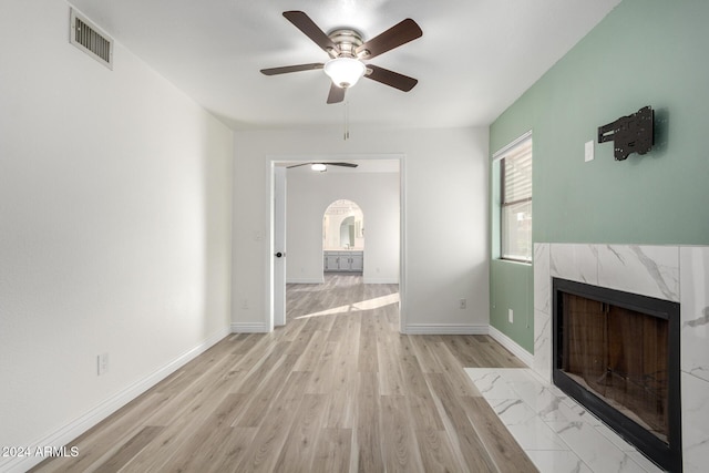 3315 E Hampton Ave, Mesa, AZ 85204 - unfurnished living room with a ceiling fan, arched walkways, a high end fireplace, and light wood finished floors