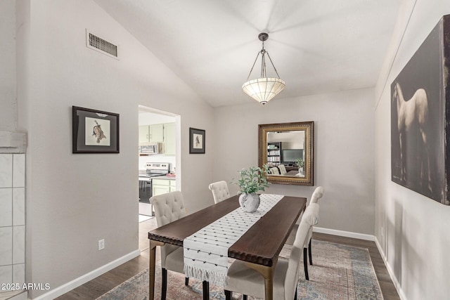 dining area with dark wood-type flooring and vaulted ceiling