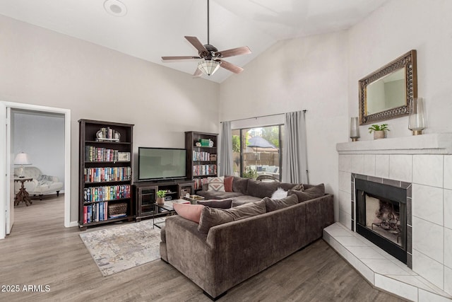 living room featuring ceiling fan, a fireplace, light hardwood / wood-style floors, and vaulted ceiling